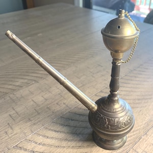 May include: An antique brass hookah with a long, angled stem and a decorative, spherical base. The hookah features a small, round bowl with a lid and a chain. The base has an etched floral design.