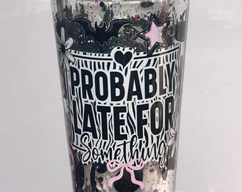 May include: A clear tumbler with a silver lid, filled with black glitter and decorative elements. The tumbler features the text "PROBABLY LATE FOR Something" in black and white, along with a bat, star, and bow design.