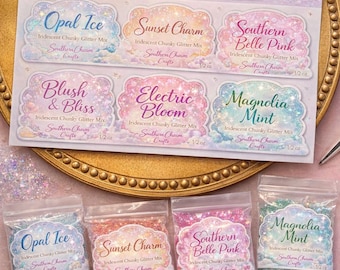 Może przedstawiać: Kolekcja iryzujących, grubych mieszanek brokatu, oznaczona jako "Southern Skies Glitter Collection". Obraz przedstawia sześć mieszanek brokatu o nazwach takich jak "Opal Ice" i "Sunset Charm". Każda mieszanka znajduje się w przezroczystej torebce z etykietą zawierającą nazwę i "Southern Charm Crafts".