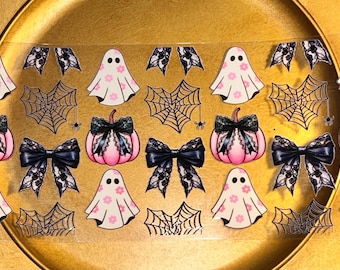 Może przedstawiać: Arkusz naklejek do zdobienia paznokci o tematyce Halloween. Wzory obejmują różowe duszki z kwiatowymi akcentami, czarne kokardy, różowe dynie z czarną koronką, pajęczyny i akcenty pająków. Naklejki są na przezroczystym tle.