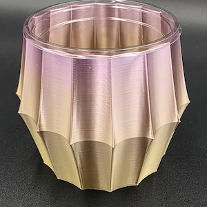 May include: A decorative, faceted planter with a clear rim. The planter features a gradient of colors, transitioning from a light yellow at the base to a soft pink at the top. The design has a geometric, modern aesthetic.