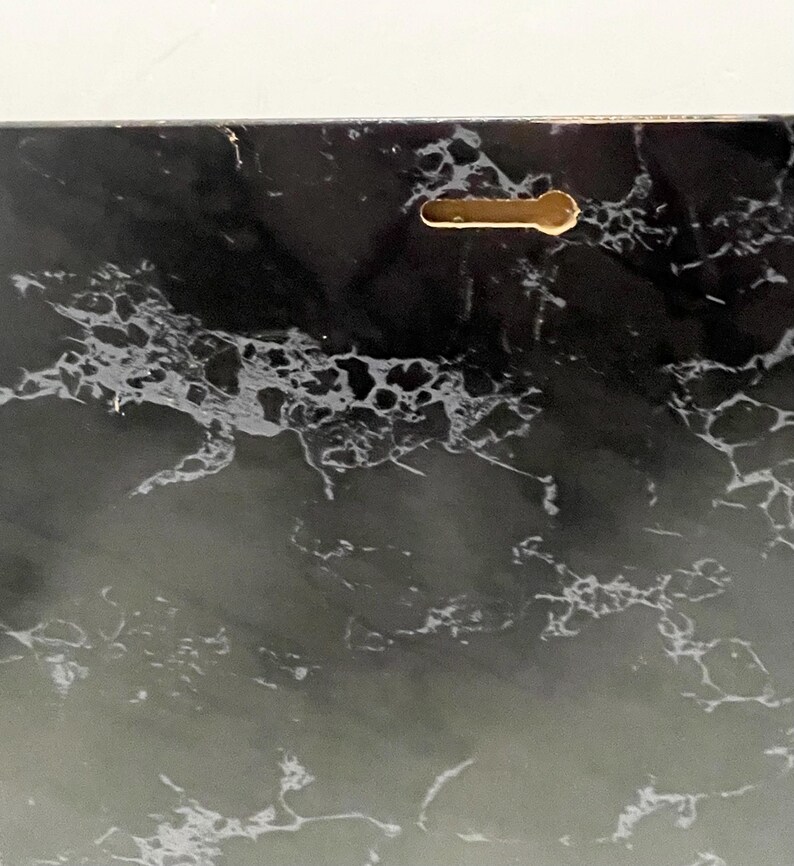 May include: A rectangular decorative panel with a black and white marble design. The panel has a keyhole-shaped hanging slot on the back for easy mounting. The marble pattern features swirling veins and a glossy finish.