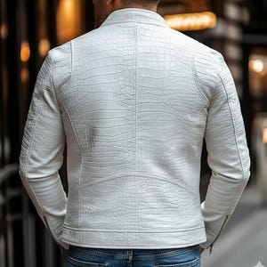 Peut inclure: Veste blanche &agrave; effet peau de crocodile. Elle pr&eacute;sente un col montant, des manches longues et une fermeture &eacute;clair sur la manche. L'image montre le dos de la veste, soulignant la texture et les d&eacute;tails du design.