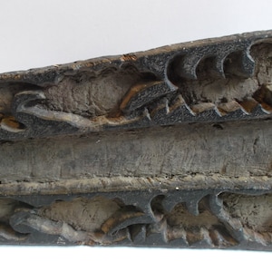 May include: A vintage wooden printing block with intricate carved designs. The block is dark brown and shows signs of wear and use.