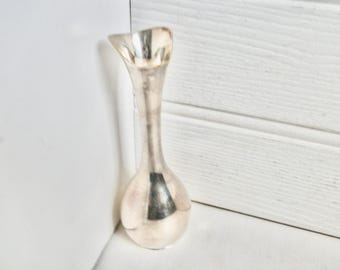Puede incluir: Un jarrón de plata con fondo redondeado y abertura acampanada. El jarrón mide aproximadamente 15 cm de alto.