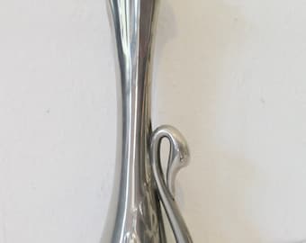 May include: A tall, silver-colored vase with a swan design. The vase has a slender neck and a flared top, with a swan's head and neck forming a graceful curve on the side. The vase is approximately 12 inches tall.