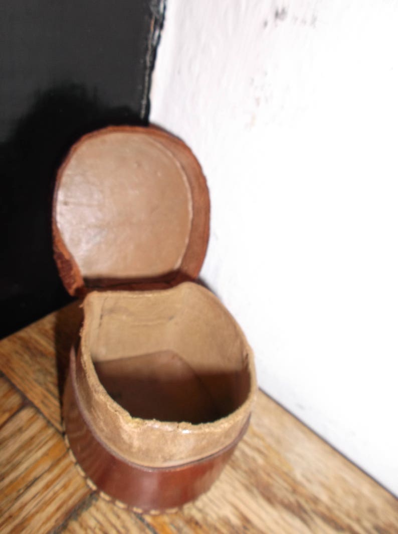 Puede incluir: Una caja de cuero marr&oacute;n con tapa con bisagras. La caja est&aacute; abierta y el interior est&aacute; vac&iacute;o.