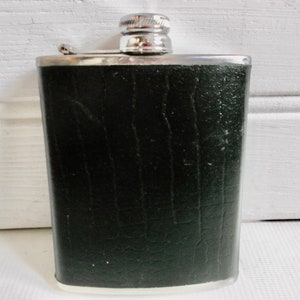 May include: A silver and black hip flask with a textured black leather finish.