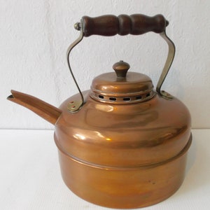 May include: A copper kettle with a wooden handle and a brass spout. The kettle has a shiny finish and a round body.