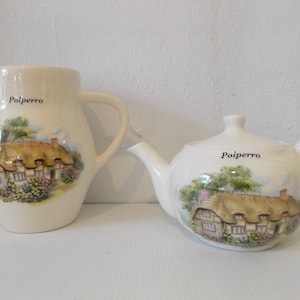 以下が含まれることがあります： 白い陶器製のティーポットとクリーマーのセットで、コテージのシーンと「Polperro」という文字が各ピースに印刷されています。