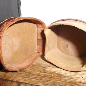 Puede incluir: Dos cajas de cuero marr&oacute;n con tapas abiertas, revelando interiores vac&iacute;os. Las cajas est&aacute;n hechas de un cuero suave y flexible y tienen un aspecto r&uacute;stico y vintage.