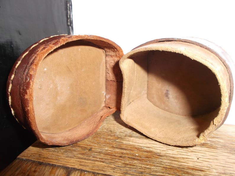 Puede incluir: Dos cajas de cuero marr&oacute;n con tapas abiertas, revelando interiores vac&iacute;os. Las cajas est&aacute;n hechas de un cuero suave y flexible y tienen un aspecto r&uacute;stico y vintage.