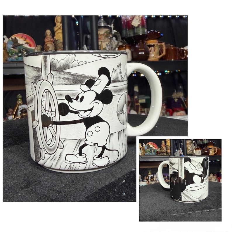 May include: White ceramic mug with a black and white illustration of Mickey Mouse steering a ship. The mug has a large, curved handle and a black rim. The design wraps around the mug.