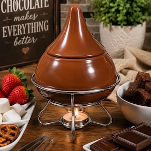 May include: A brown ceramic chocolate fondue pot with a lid, set on a silver metal stand. A lit candle sits beneath the pot. The image includes strawberries, marshmallows, pretzels, and chocolate squares, suggesting a dessert theme.
