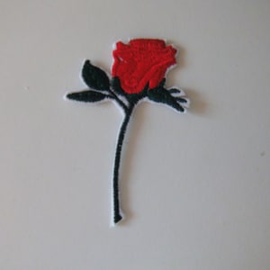 Könnte beinhalten: Rote gestickte Rose mit grünen Blättern und einem schwarzen Stiel auf weißem Hintergrund.