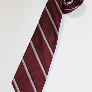 May include: A burgundy striped tie with white and black stripes. The tie is made of a silky material and has a pointed tip.