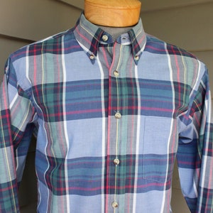 May include: A long-sleeved button-down shirt with a plaid pattern in shades of blue, green, red, and white.