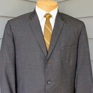 May include: A dark gray suit jacket with a single button closure. The jacket has a brown striped tie and a white collared shirt underneath.