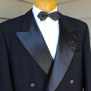 May include: A black double-breasted tuxedo jacket with a satin lapel and a black bow tie.