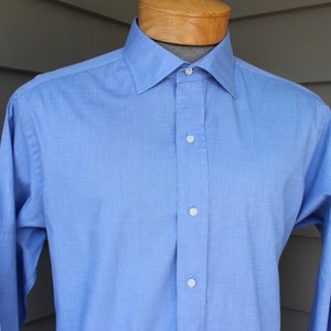 May include: A light blue long-sleeved dress shirt with a button-down collar and white buttons.