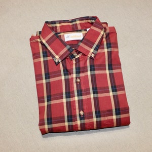 May include: A red, black, and cream plaid button-down shirt with a label that reads "Saddleback".