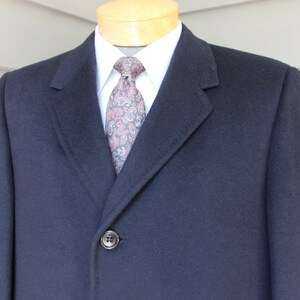 May include: A navy blue overcoat with a single button closure. The coat has a classic, tailored fit and is made of a high-quality fabric.