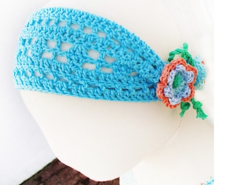 May include: A light blue crochet headband with an open weave design. The headband is adorned with a cluster of crocheted flowers in shades of orange, blue, and green. The text "Sophie and Me © Pdf PatternDesign" is at the bottom.