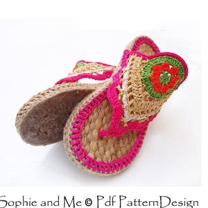 May include: A pair of crocheted sandals with a pink, green, and orange floral design. The sandals are made of a natural material, possibly straw or jute.