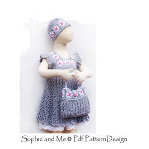 K&ouml;nnte beinhalten: Ein graues H&auml;kelkleid mit rosa Blumenapplikationen, eine passende graue H&auml;kelm&uuml;tze mit rosa Blumen und eine graue H&auml;kelhandtasche mit rosa Blumen. Das Kleid hat einen wei&szlig;en Spitzenbesatz. "Sophie and Me &copy; Pdf Pattern Design"