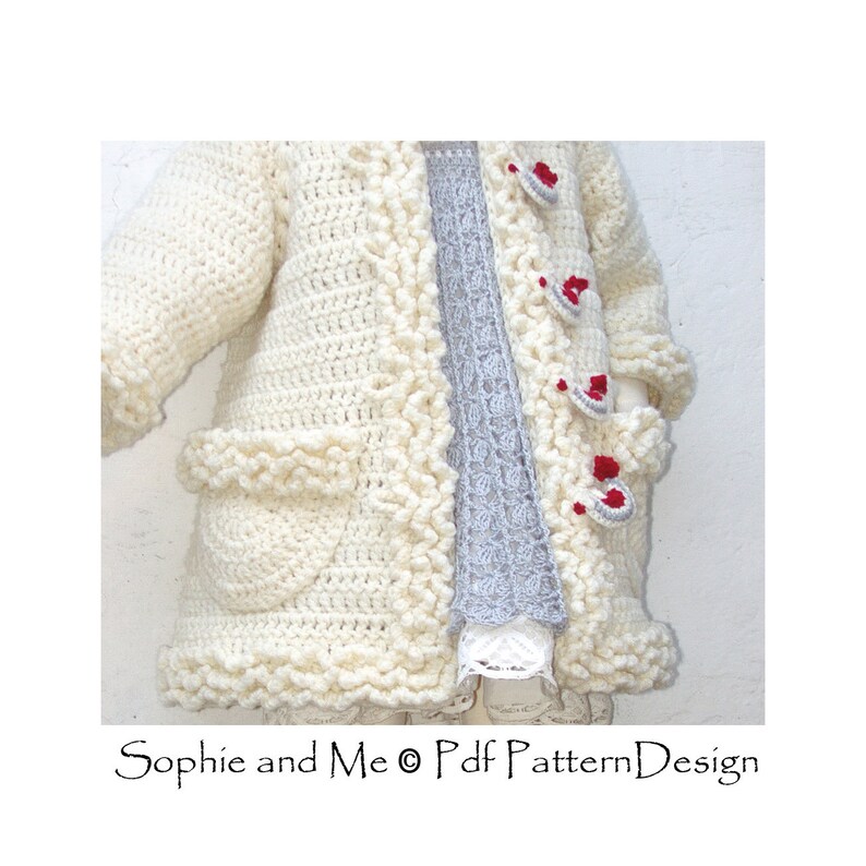 May include: A white crocheted cardigan with a scalloped edge and red buttons. The cardigan has pockets on the front and is shown being worn over a gray shirt.