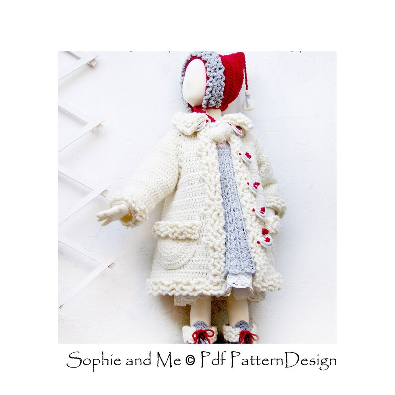 May include: A white crocheted coat with a ruffled trim, red heart buttons, and a matching white crocheted hat. The coat is worn by a doll on a white background.