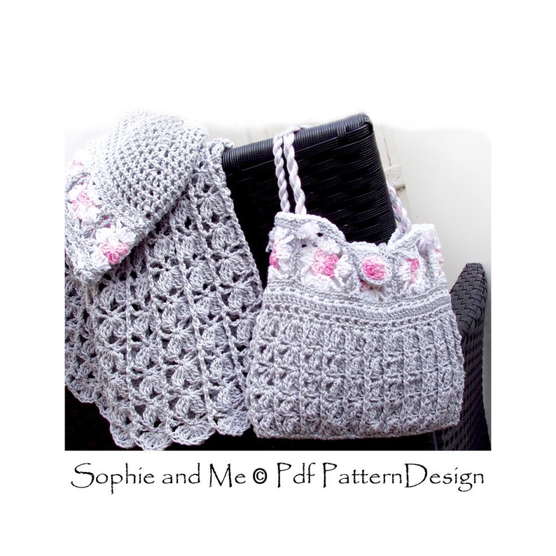 K&ouml;nnte beinhalten: Eine graue geh&auml;kelte M&uuml;tze und eine passende Handtasche mit rosa Blumenapplikationen. M&uuml;tze und Tasche liegen auf einem schwarzen Korbstuhl. "Sophie and Me &copy; Pdf Pattern Design" steht unten im Bild.