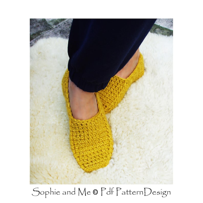 May include: A pair of yellow crocheted slippers on a white fluffy rug. The slippers are made with a simple stitch pattern and have a rounded toe.