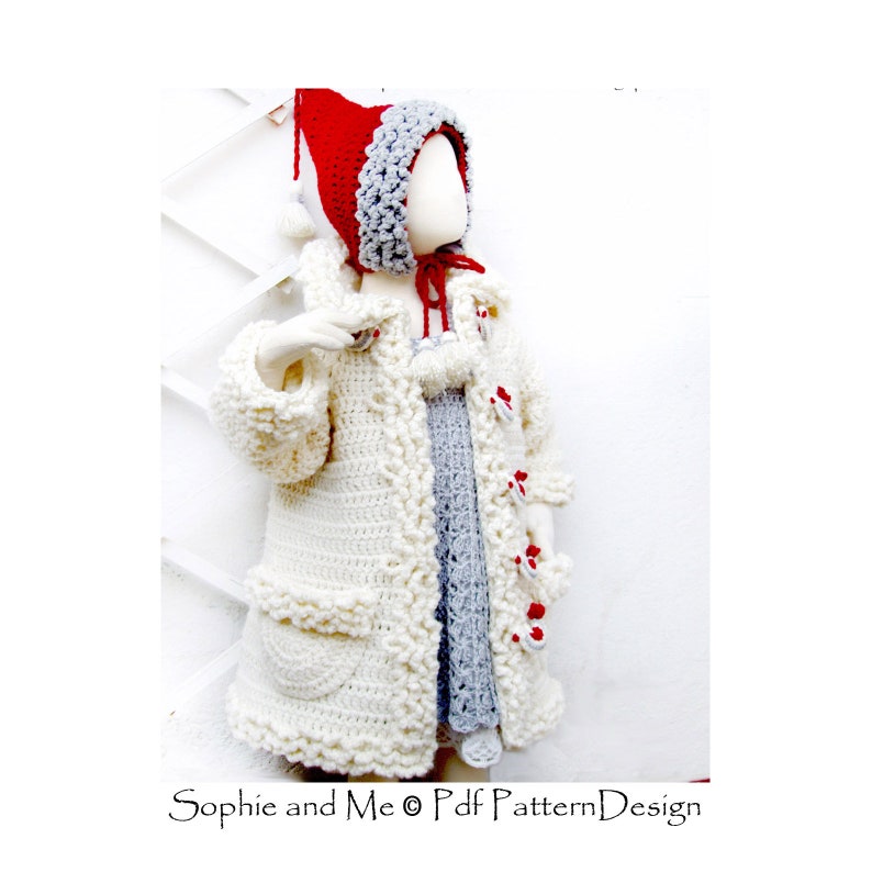 May include: A white crocheted coat with a red and gray crocheted hood. The coat has a pocket on the front and is decorated with red and white pom-poms.  "Sophie and Me &copy; Pdf Pattern Design" is printed on the bottom of the image.