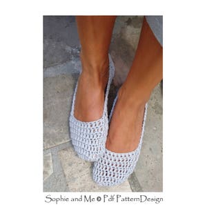 Könnte beinhalten: Ein Paar gehäkelte graue Ballerinas. Die Ballerinas sind mit einem zarten Lochmuster gearbeitet.