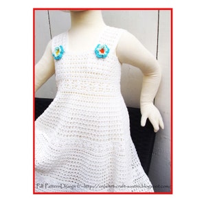 May include: White crochet dress with a sleeveless design and a scalloped hem. The dress has two small crocheted flowers on the bodice, one blue and one yellow.