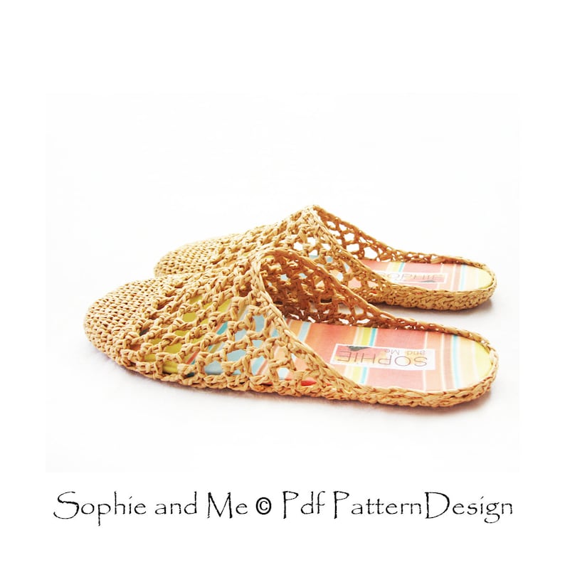 May include: A pair of beige crocheted slippers with a woven pattern. The slippers have a colorful striped insole with the text "Sophie and Me" printed on them.