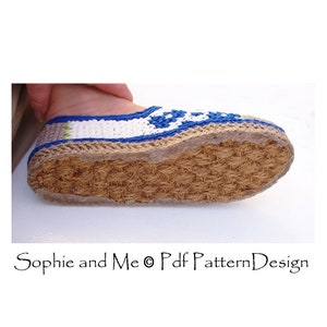 Puede incluir: Primer plano de la parte inferior de una zapatilla de crochet con suela de fibra de coco. La zapatilla es blanca con detalles azules y verdes.
