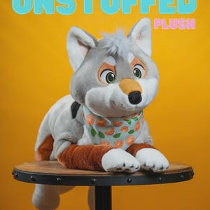 Peut inclure: Une peluche de loup avec une fourrure grise et blanche, des accents orange et un bandana bleu clair avec des motifs de tranches d'orange. Le texte "UNSTUFFED PLUSH" est affich&eacute; au-dessus du jouet sur un fond jaune.