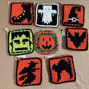 Pode incluir: Um conjunto de oito bases para copos em croché, quadradas e circulares, com motivos de Halloween, incluindo uma bota preta, um fantasma branco, um chapéu de bruxa, uma cara de Frankenstein, uma abóbora laranja, um morcego, uma bruxa e um gato preto.
