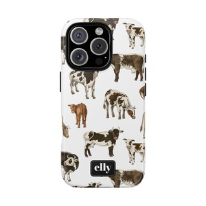 Könnte beinhalten: Weißes Handycase mit einem sich wiederholenden Muster von illustrierten Kühen in Braun, Schwarz und Weiß. Das Case hat einen schwarzen Rand und der Markenname "elly" ist unten aufgedruckt. Die Kühe sind in verschiedenen Posen.