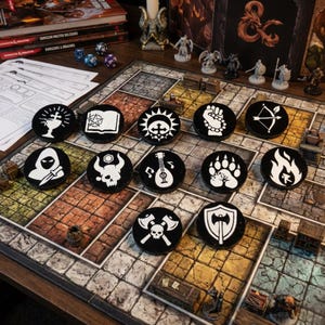 May include: A tabletop role-playing game setup featuring a game board, dice, miniature figurines, and a collection of black tokens with white symbols. The tokens display various icons like a fist, bow and arrow, and a skull with axes.