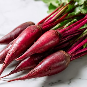 May include: A close-up shot of several fresh beets with vibrant red roots and green leafy tops. The beets are arranged on a white marble surface, showcasing their natural colors and textures. The image highlights the freshness of the produce.