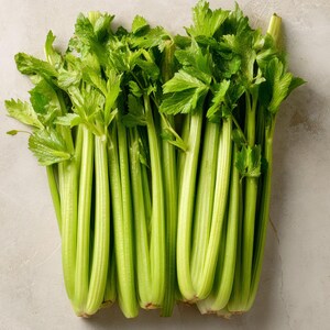 May include: A fresh bunch of celery with vibrant green stalks and leafy tops. The celery is arranged in a neat bundle, showcasing its natural texture and color. The image is a top-down view, highlighting the freshness of the produce.