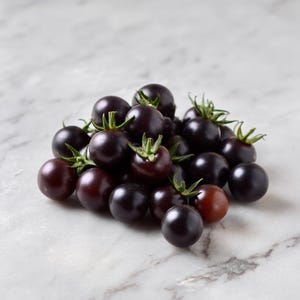 May include: A pile of small, dark purple tomatoes with green stems and leaves. The tomatoes have a smooth, shiny surface and vary in color from deep purple to reddish-brown. The tomatoes are arranged on a white marble surface.