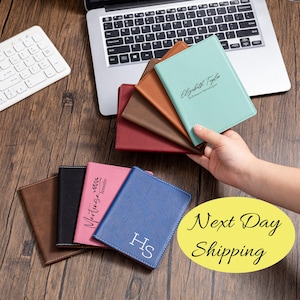 May include: A collection of personalized passport holders in various colors, including brown, black, pink, and blue. One holder is held up, showing the name "Elizabeth Taylor" and the title "Software Developer". The phrase "Next Day Shipping" is also visible.