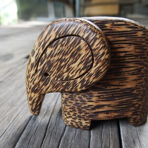 May include: A wooden elephant figurine carved from dark brown wood with a striped pattern. The elephant's trunk is curled up and its ears are large.