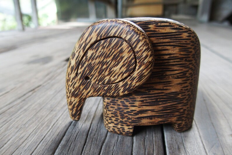 May include: A wooden elephant figurine carved from dark brown wood with a striped pattern. The elephant's trunk is curled up and its ears are large.