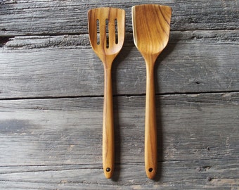 Peut inclure: Deux ustensiles de cuisine en bois, une spatule fendue et une cuillère, sur une surface en bois vieilli.