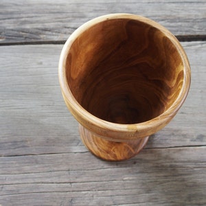 May include: A wooden bowl with a natural wood finish. The bowl is empty and has a rounded bottom.